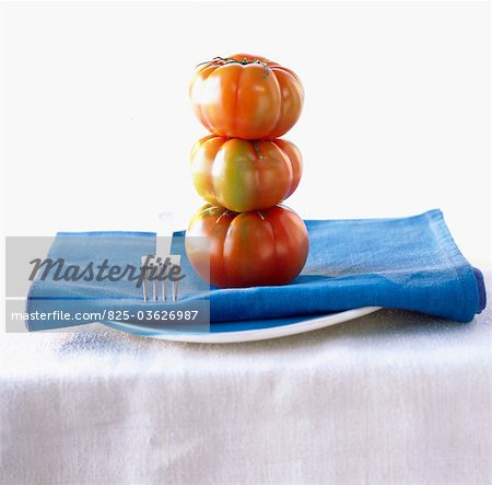 Stacked tomatoes, napkin and fork