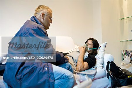 Emergency on-call doctor administering oxygen to patient in home