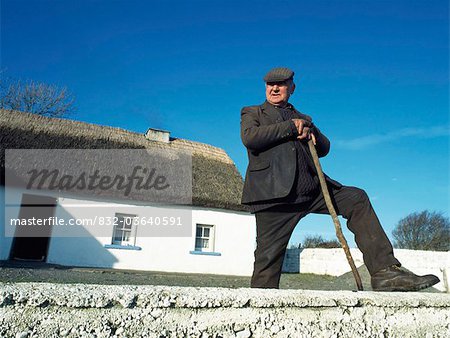 Co. Galway, Irland;Landwirt steht außerhalb seines Reetdachhaus