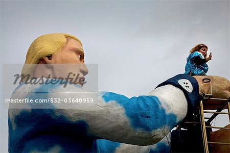 Dublin, Irland; Eine Frau tanzt am Anfang ein Riesen Mann Statue In einer Parade