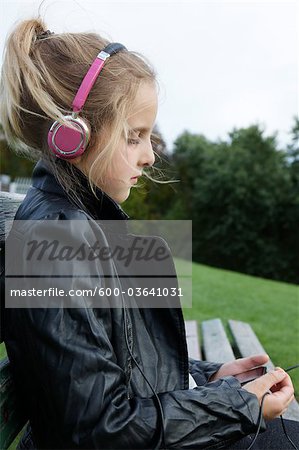 Young Girl Sitting Outside Listening to Music