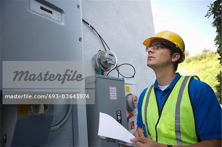 Maintenance worker reads meter of solar generation unit in Los Angeles, California