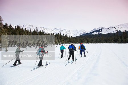 A group of friends cross country ski and snowshoe on the multi-use Moose Meadow trail near the Alyeska Hotel in Girdwood, Alaska, Spring