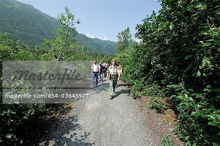 Female Forest Service guide leading hikers on a trail to Spencer Glacier as part of the Alaska Railroad's Spencer Whistle Stop Camping tour, Southcentral Alaska, Summer