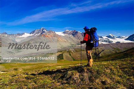 Male backpacker views Gulkana Glacier while hiking in the Alaska Range, Southcentral Alaska, Summer/n