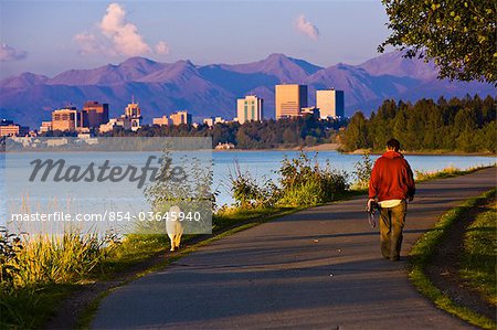 People jogging, walking and biking on the Tony Knowles Coastal Trail with Downtown Anchorage skyline in the distance, Anchorage, Southcentral Alaska, Summer