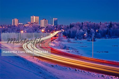 Twilight view of traffic on Minnesota Blvd. with downtown Anchorage in the background, Southcentral Alaska, Winter