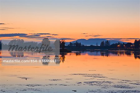 View of sunset reflected in Westshester Lagoon with Mount Susitna in the distance, downtown Anchorage, Southcentral Alaska, Summer