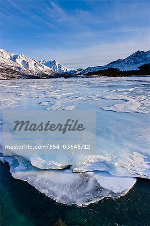 Vue des sastrugis vent sculpté des crêtes dans la neige qui recouvre les surgelés Phelan Creek à côté de l'autoroute Richardson comme elle se dirige dans la chaîne de l'Alaska, centre-sud de l'Alaska, hiver