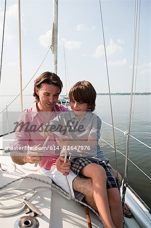 Father and son on board yacht with rope