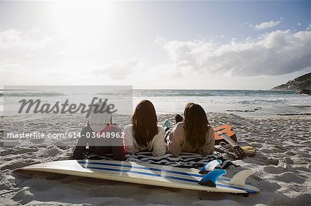 Trois jeunes filles se trouvant sur la plage avec planche de surf