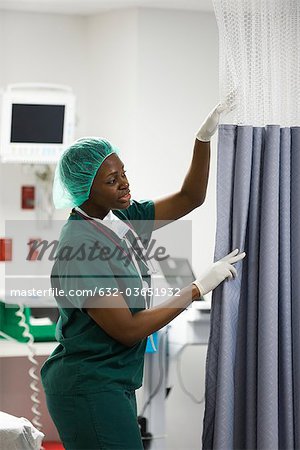 Nurse closing privacy curtain in hospital room