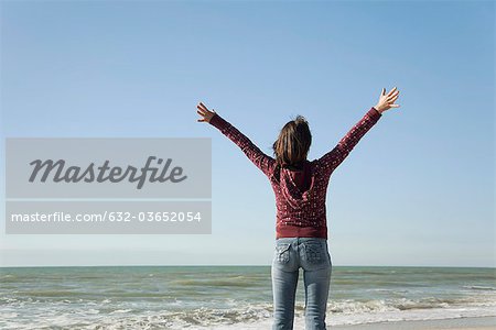 Femme debout sur la plage avec les bras levés