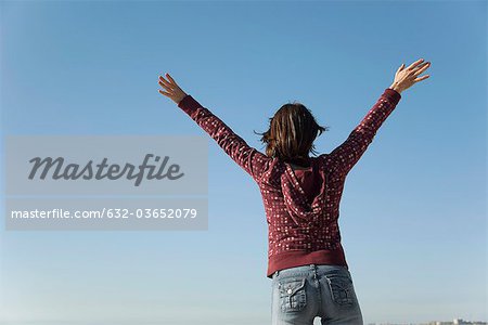 Woman standing outdoors with arms raised in the air