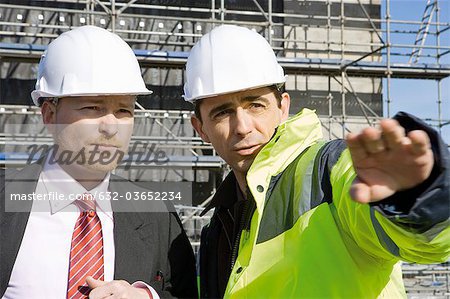 Building contractor talking to businessman at construction site