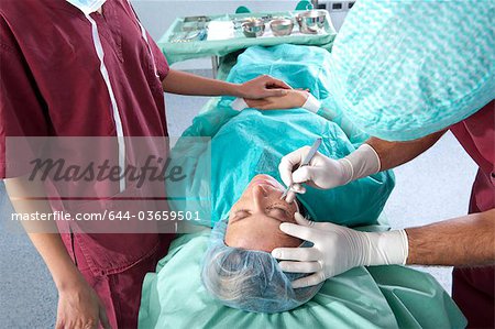 Chirurgien avec scalpel sur le visage du patient.