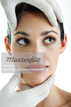 Port chirurgical des mains gants holding jeune visage femme