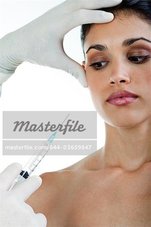 Hand holding botox syringe to young woman's face