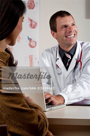 Doctor at laptop with patient in office