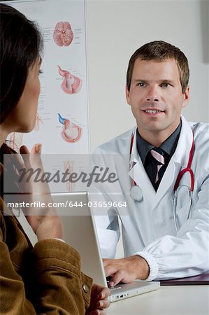 Doctor at laptop with patient in office