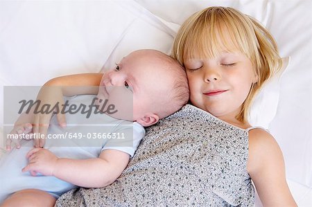 Girl with her baby brother in bed