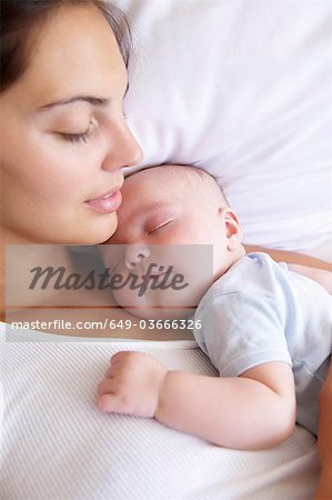 Woman and her baby sleeping in bed