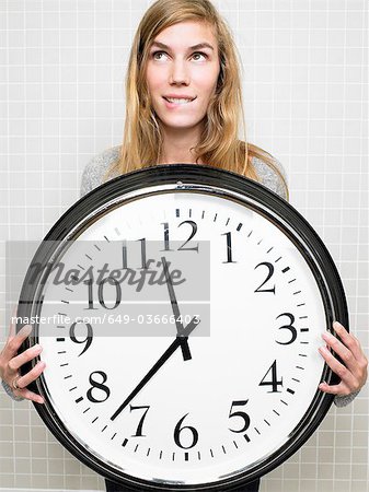 Femme tenant une grande horloge