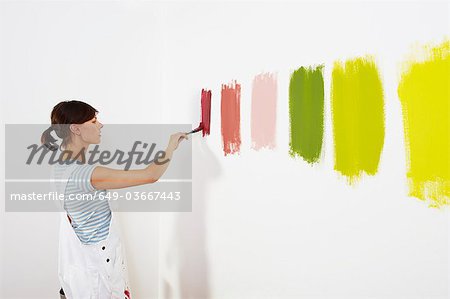 Woman painting colour swatches on wall