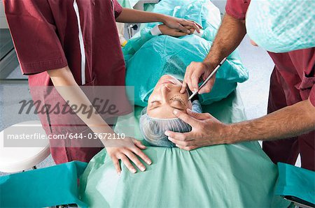 Surgeon marking incision lines on face in operating room