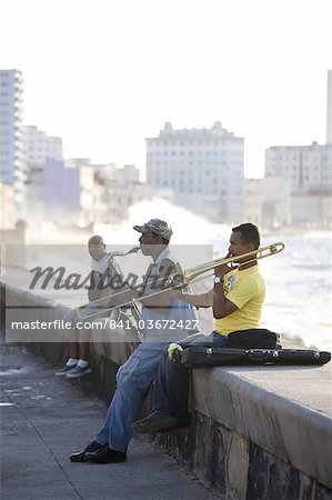Musiciens sur le Malecon jouant saxaphone et trombone avec vagues qui s'écrasent contre la rive dans le fond, la Havane, Cuba, Antilles, Caraïbes, Amérique centrale