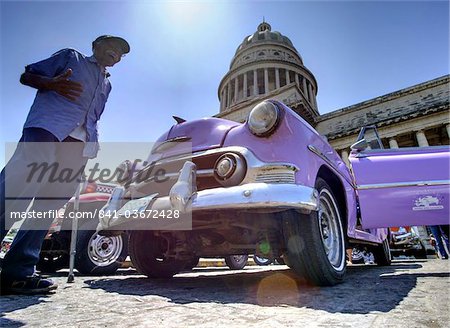 Low angle shot of The Capitolio with classic American car and old man in foreground, Havana, Cuba, West Indies, Caribbean, Central America