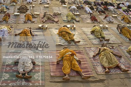 Students of a Sanskrit school performing the savasana (corpse) posture during daily yoga lesson at sunrise, on the ghat of Varanasi, Uttar Pradesh, India, Asia