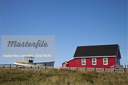 Maritime house painted red with boat on lawn, Iles de la Madeleine (Magdalen Islands), Gulf of St. Lawrence, Quebec, Canada, North America