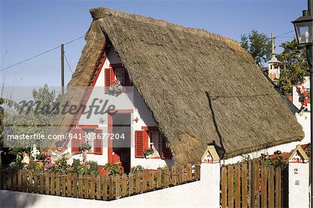 Ein Mann von Madeira befindet sich außerhalb eines traditionellen Hauses Palheiro a-förmige in der Stadt von Santana, Madeira, Portugal, Europa