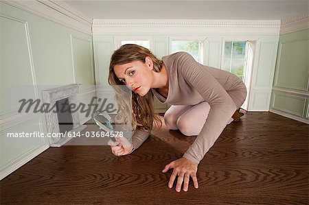 Young woman in small room with magnifying glass