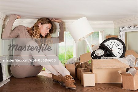 Young woman with box of objects in small room