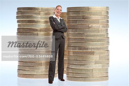 Businesswoman Standing in front of Stacks of Large Coins