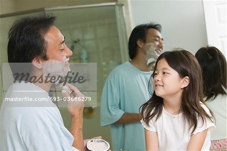 Daughter watching father apply shaving cream in bathroom