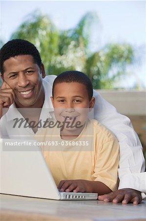 Père et fils assis sur le patio Using Laptop, portrait
