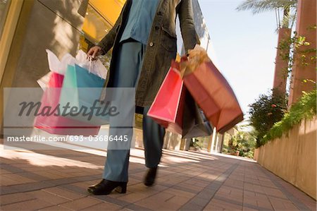 Woman carrying shopping bags, low section