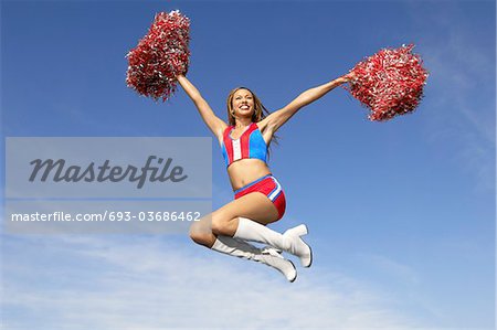 Cheerleader mit Pom Poms ausgelöst, mittleren Luft springen