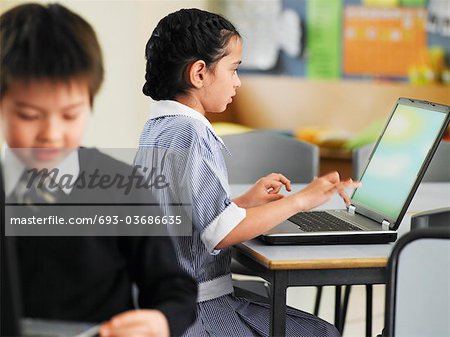 Elementary students using laptops in classroom
