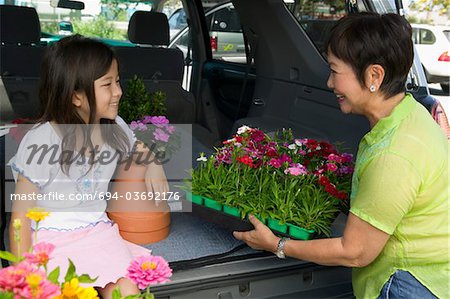 Grandmother and granddaughter loading flowers into back of SUV