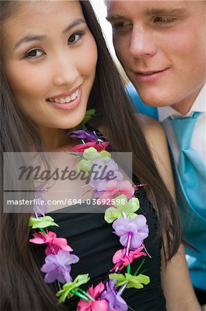 Well-dressed teenage couple wearing leis outside school dance
