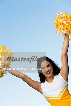 Smiling Cheerleader rising pom-poms, (portrait)