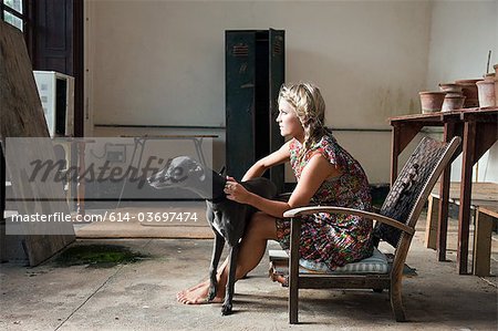 Junge Frau sitzt auf dem Stuhl mit Hund