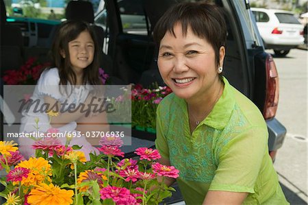 Grandmother and granddaughter loading flowers into back of SUV, portrait