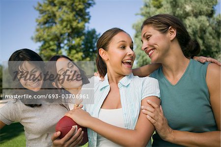 Four women in park, one woman holding football.