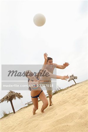 Couple Diving for Volleyball on Beach, tilt view