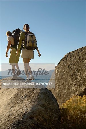 Couple hiking on boulders at coast